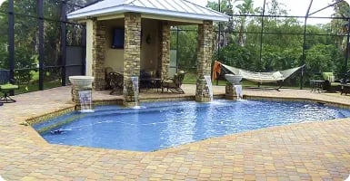 Pool deck pavers around a stone-column cabana