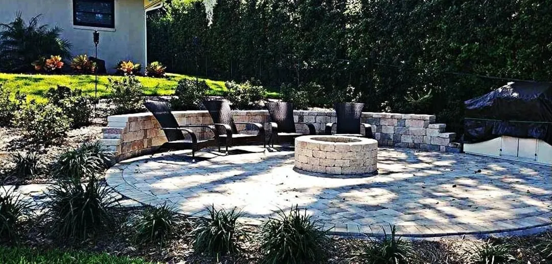 Round paver fire pit with seating, gravel and landscaping